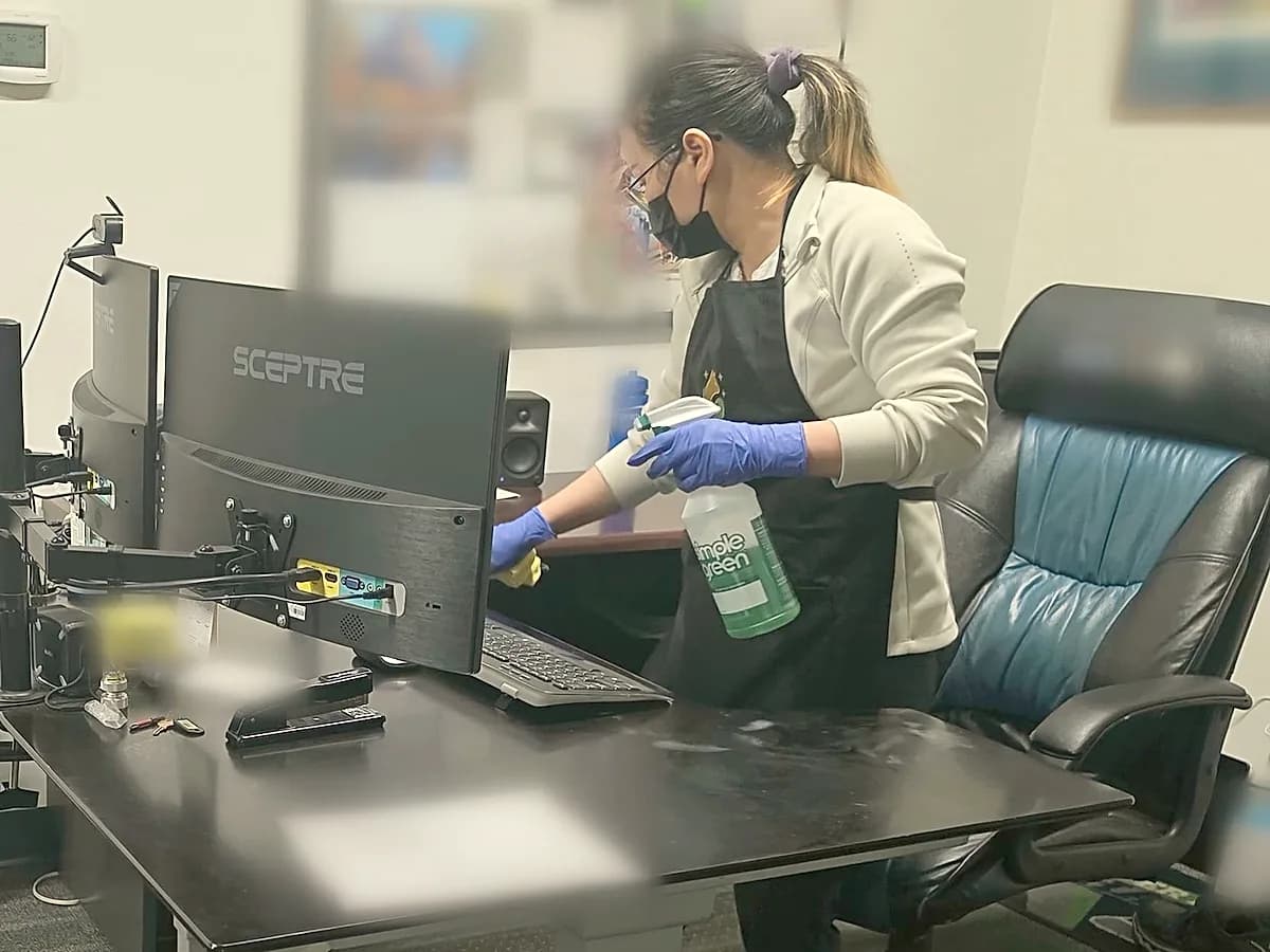 Janicat cleaner wiping down an office desk and monitor